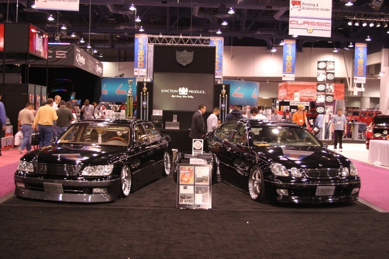 Junction Produce booth at SEMA 2004 with a black Lexus LS400 on the left and GS400 on the right